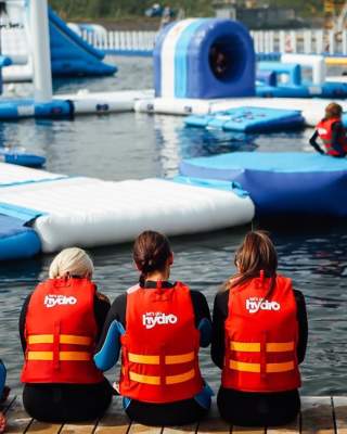 Image shows children wearing life jackets, sitting on the edge of the lake
