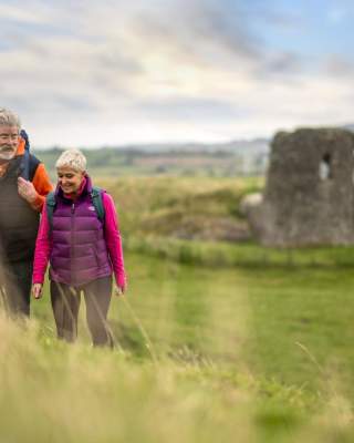 A couple enjoying a walk around the site of Harry Avery's castle with ruins in the background
