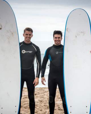 Two surfers pose with their boards in front of the sea Whiterocks Beach, Portrush, County Antri