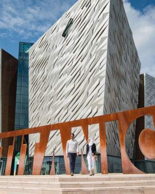 External Image of a couple visiting Titanic Belfast, at the Titanic Belfast sign.