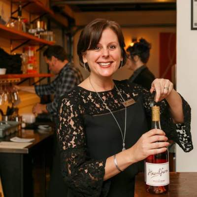 Julie Dalrymple smiles with a bottle of Hazelfern rosé at an upscale event