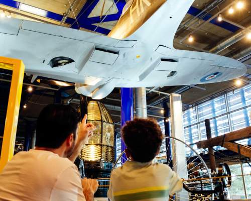 A father and son look up at the underside of a WWII plane in the ThinkTank in Birmingham