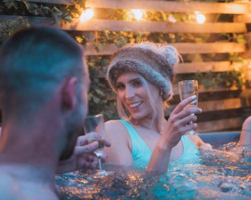 A couple enjoy a glass of wine in a hot tub at Cotswold Farm Park