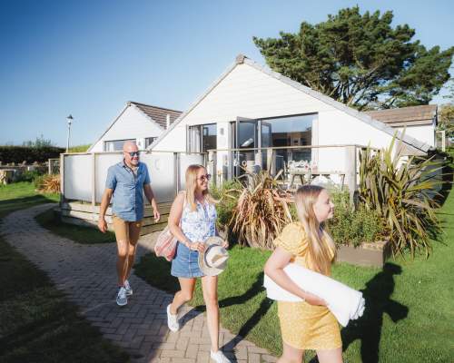 family outside lodge in Holiday Park in summer walking