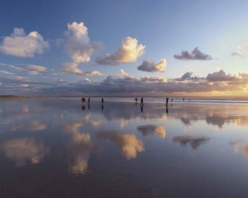 people at saunton beach in the sea at sunset