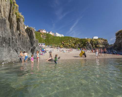 a beach in woolacombe with people swimming and enjoying the sun