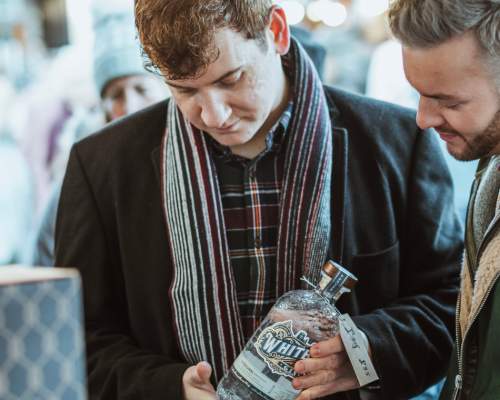 Two men shopping at a drinks stall at the Beverley Festival Christmas