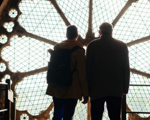 Two people looking out of the huge rose windows on a roof tour of Beverley Minster