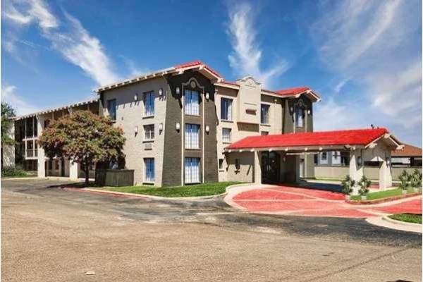 a welcoming Amarillo hotel with a red roof entrance and covered drive, set against wide Texas skies with wispy clouds stretching overhead