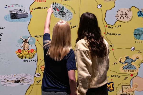 Two girls looking at mural of michigan map