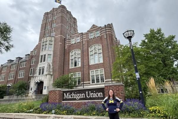 Woman stands in front of Michigan Union sign and building, and smiles for the camera.