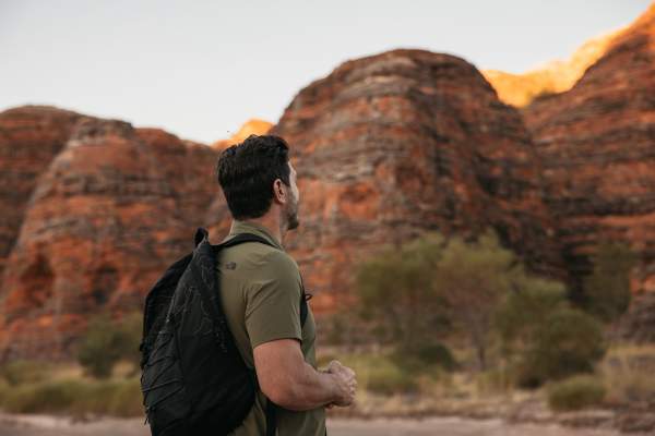 A man stands looking at the striped domes of the Bungle Bungle Range in Purnululu National Park