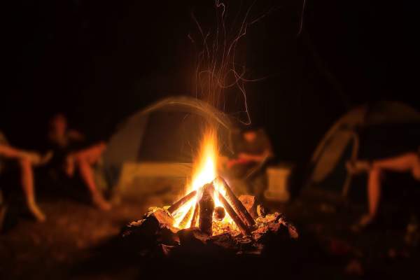 Campers sit around a campfire on a Rough as Guts Tagalong Tour