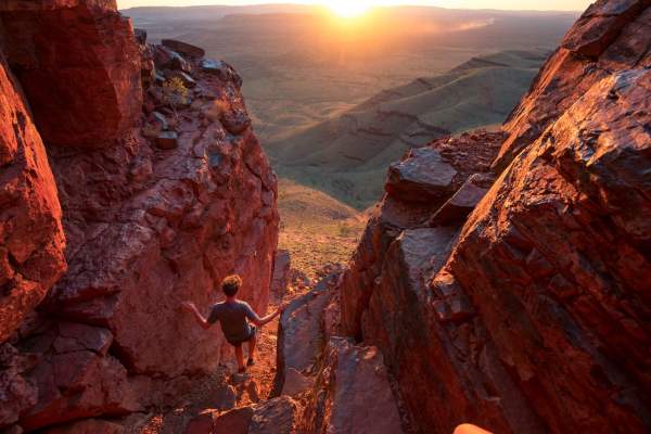 A man descends through the rocks from the summit of Mt Bruce; a sweeping landscape can be seen beyond.