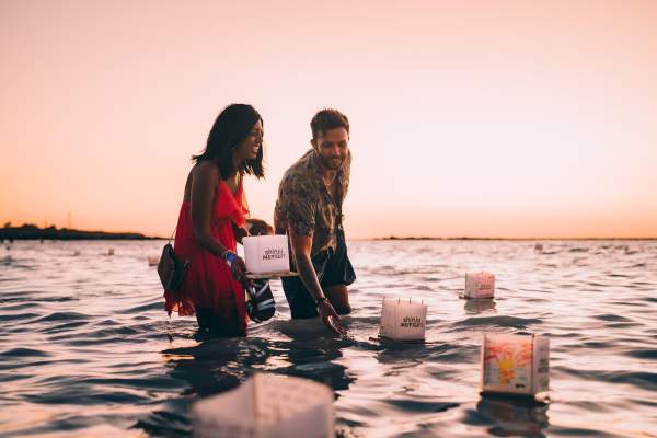 A couple wading into the ocean at Gantheaume Point, Broome to place their floating lanterns into the ocean at sunset.