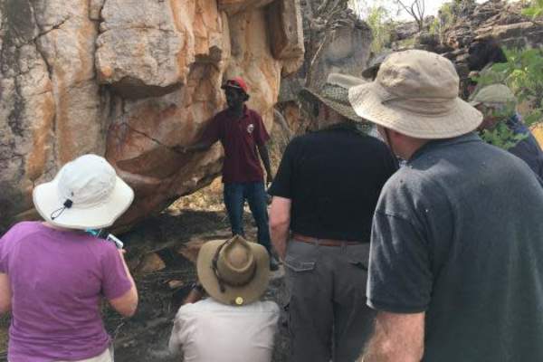 Four tour guests looking at rock art in the remote Kimberley with their Unguu Ranger tour guide hosting the tour