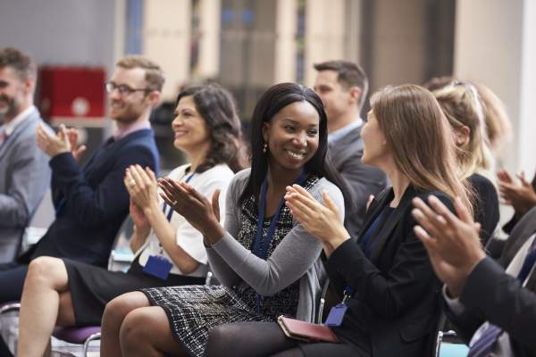 Attendees sitting in a meeting clapping