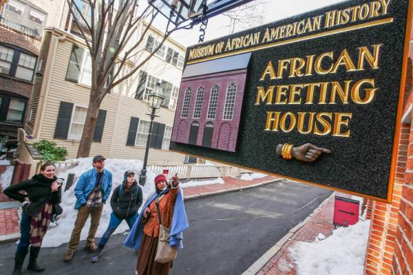 4 people looking at a sign that reads "Museum of African American History; African Meeting House."
