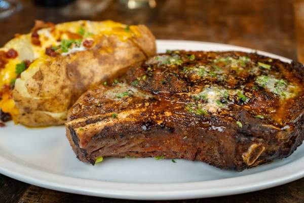 a dinner plate with a baked potato and steak