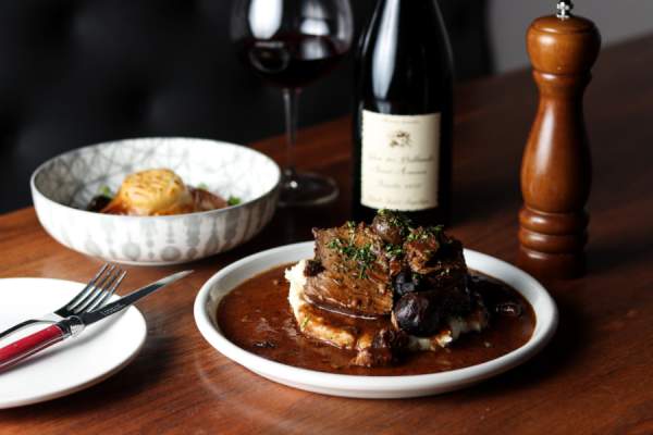 Plated dinner table with steak covered in sauce and mushrooms on top of potatoes.