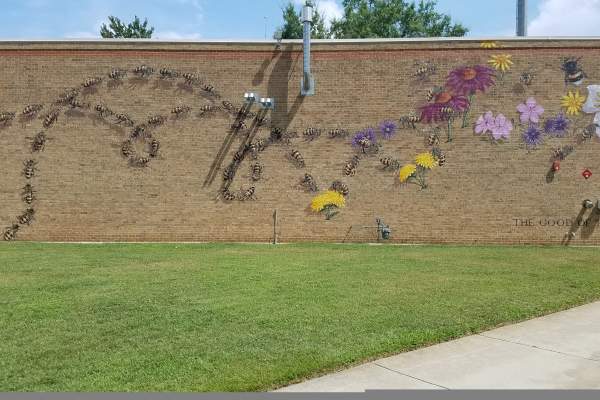Outdoor mural depicting bees and titled Good of the Hive