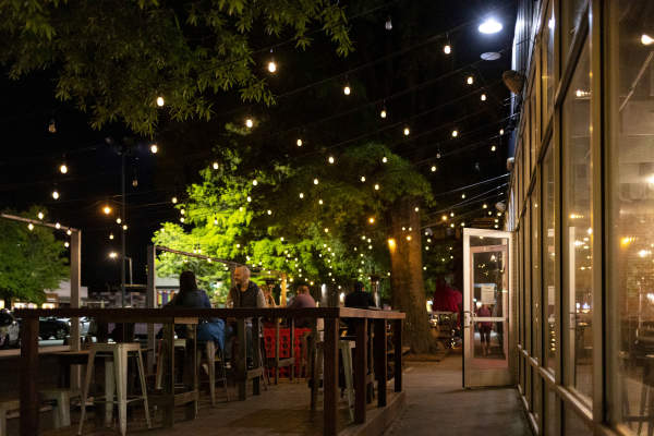 people dining outside under string lights
