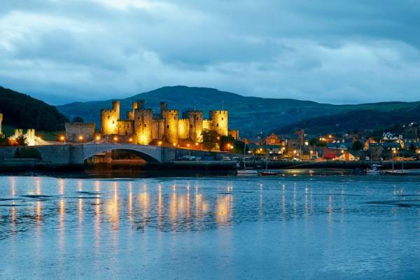A view across the water of Conwy Castle at night, lit up