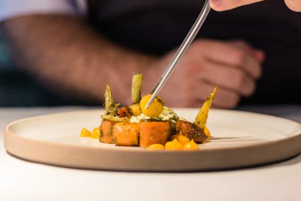 View of a dish being delicately prepared by a chef