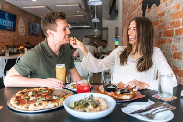 Girlfriend feeding boyfriend pizza at Wild Rabbit Pies & Pints