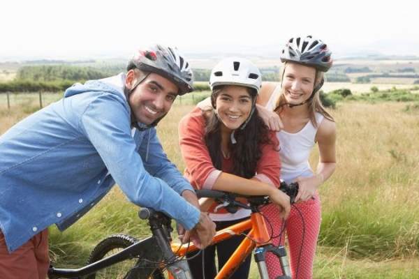 three people with bikes cycling through the countryside