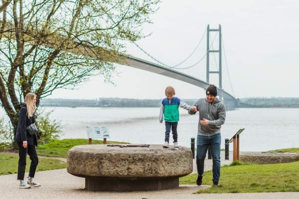 A family playing with the Humber Bridge in the background