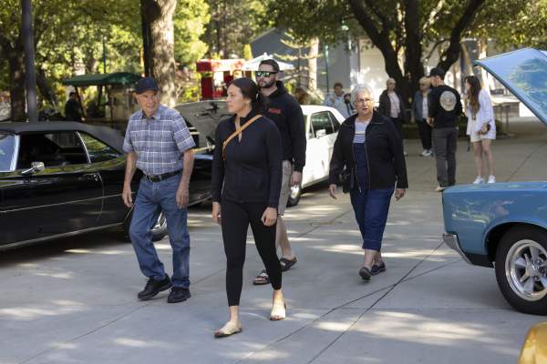 A group of people walk through rows of classic cars at Gilroy Gardens