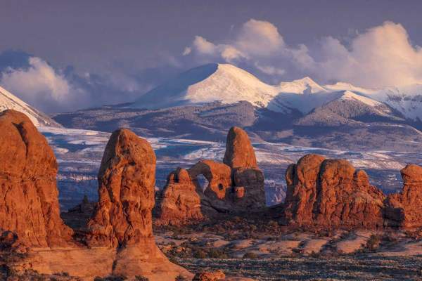 A view of The Windows section of Arches National Park, with the snow-covered La Sal Mountains in the background.