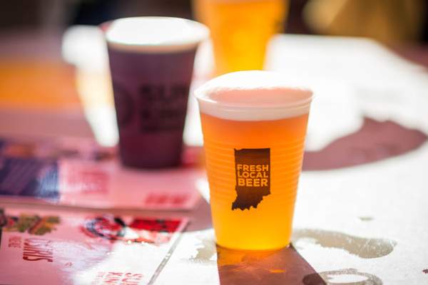 Two plastic cups of beer, one reads "Fresh Local Beer" on a graphic of Indiana