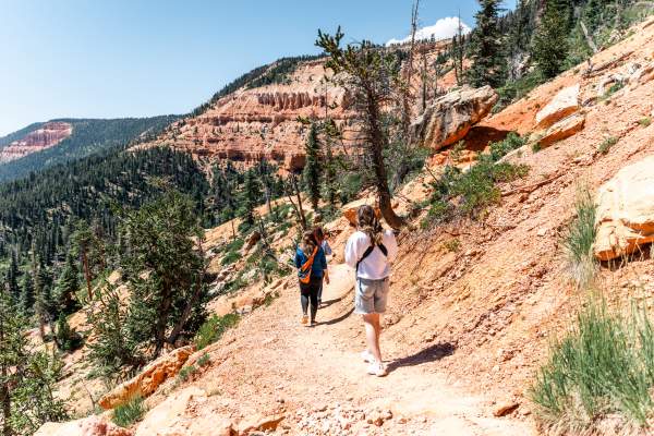Hikers walk among red rock on the Cascade Falls Trail at Navajo Lake in Dixie National Forest.