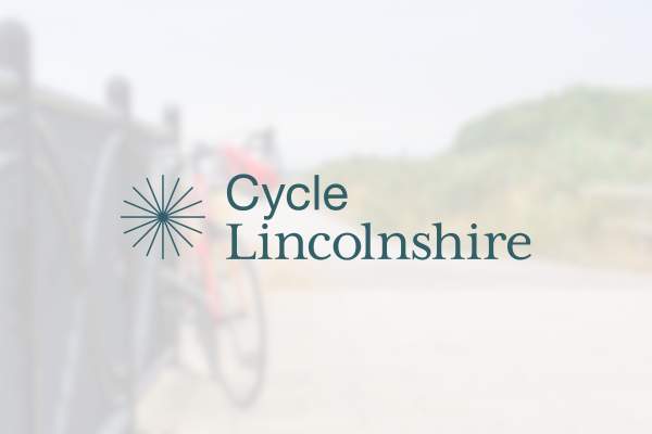 The Cycle Lincolnshire logo in front of a blurred image of a bicycle.