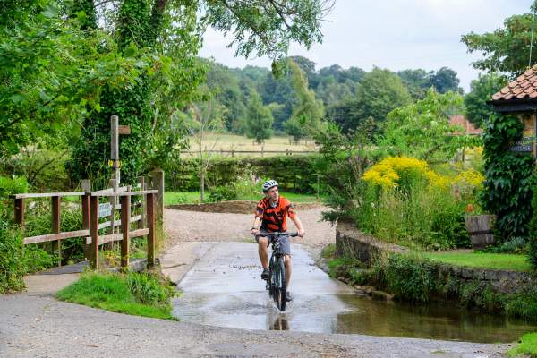 Man cycling through puddle in rural village