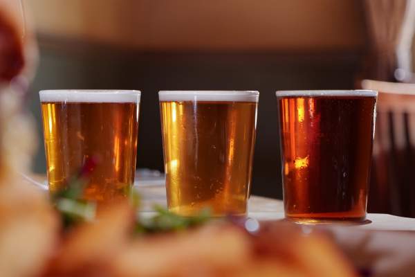 A close up image of three pints of beer inside a pub