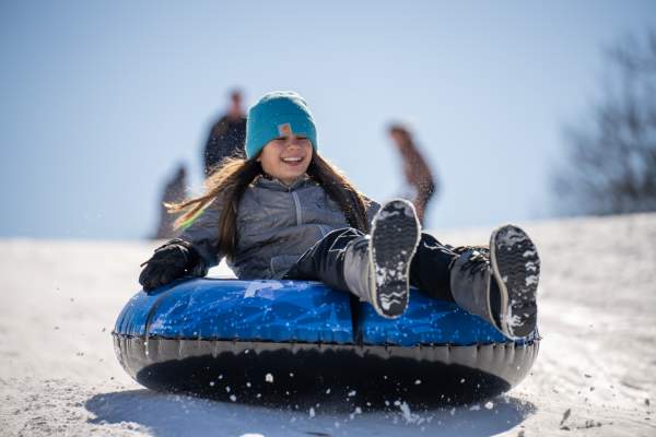 girl on sled going down snow hill