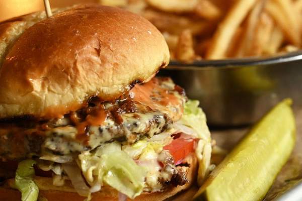 Close shot of burger, fries and a pickle spear