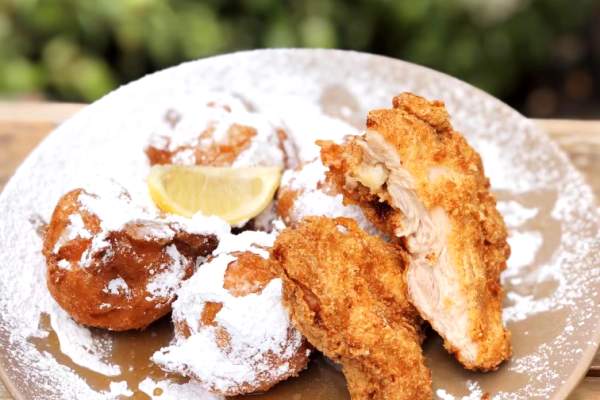 Fried Chicken and Beignets with powdered sugar on a round plate