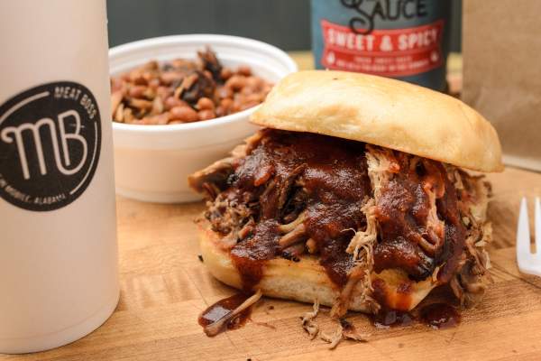 BBQ sandwich with a side of baked beans and a drink