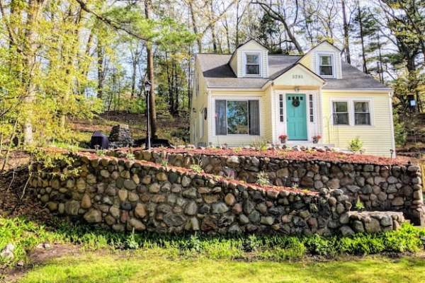 Yellow house on hill with large field stone wall in front