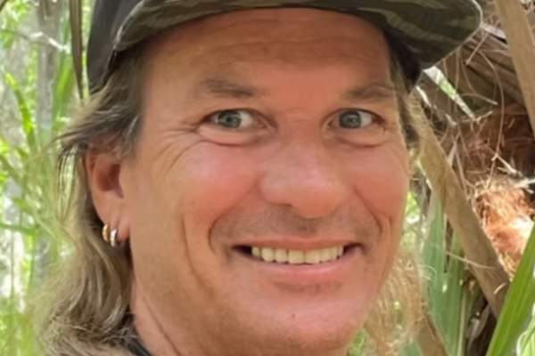 Close-up portrait of Damon Meri wearing a cap and smiling outdoors.