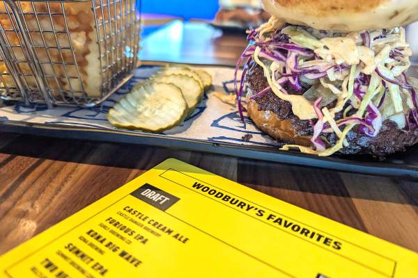 Topgolf restaurant order of loaded burger and French fries with menu places on the table titled "Woodbury's Favorites"