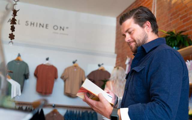 A man looks at a book while shopping in a boutique