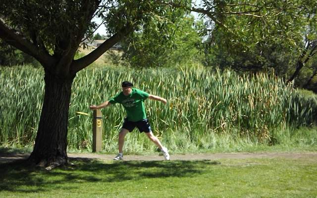 A mad tees off with his flying disc at a disc golf course