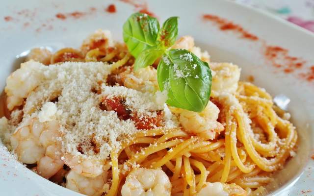 Bowl of spaghetti with sauce and shrimp, topped with fresh basil