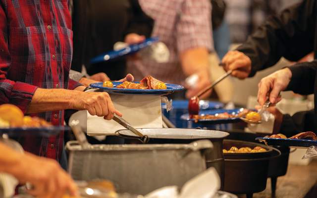 People fill their plates with food at the chuck wagon dinner