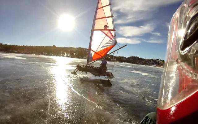 Frozen lake reflecting the morning sun with a man on an ice boat enjoying himself.